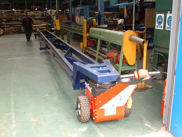 Power Pusher moving steel bars from vehicle unloading point to warehouse storage
